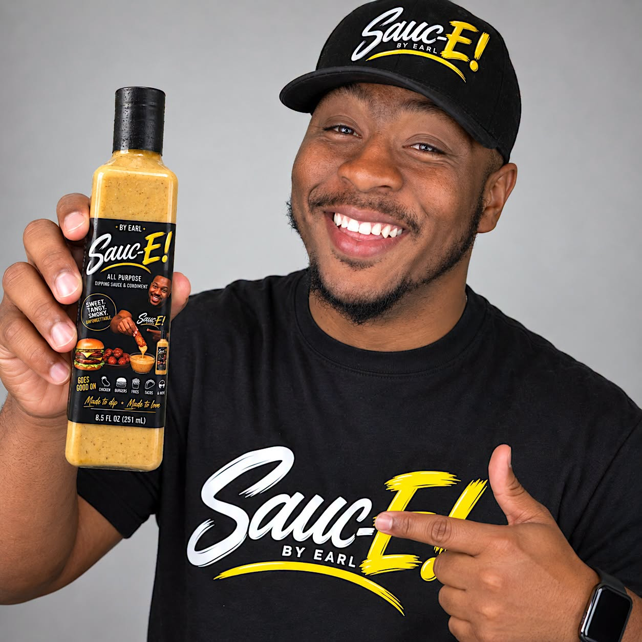 Earl smiling and holding a bottle of Sauc-E!